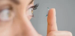 mulher colocando lente de contato no olho com o dedo