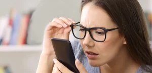 mulher de oculos segurando celular na mao forcando visao